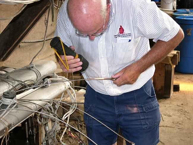 A man shines a flashlight on a sliver rod