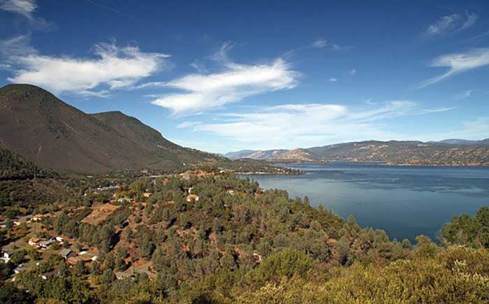 View of a blue lake, small houses dot the foreground with moutains in the background