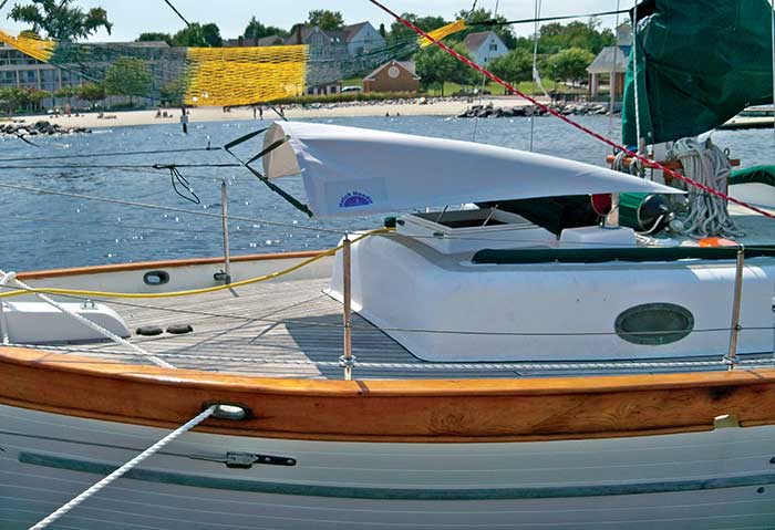 White canvas hanging over the open hatch of a sailboat tied to a dock