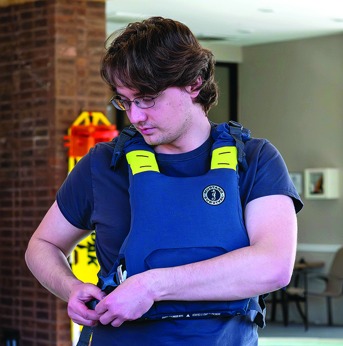 Young adult Caucasian male strapping on a gray and yellow life jacket