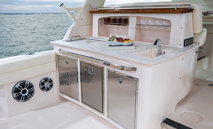 White wet bar with stainless steel drawers and cabinets on a white vessel on open waters. 