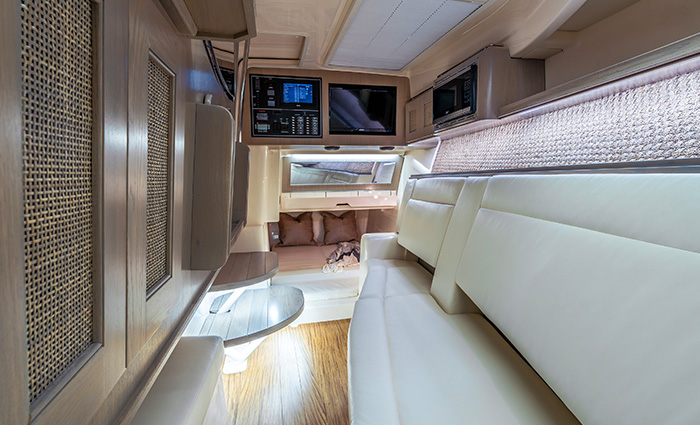 Inside the cabin of a vessel featuring a television, track lighting, seating area, hard wood floors and audio system.