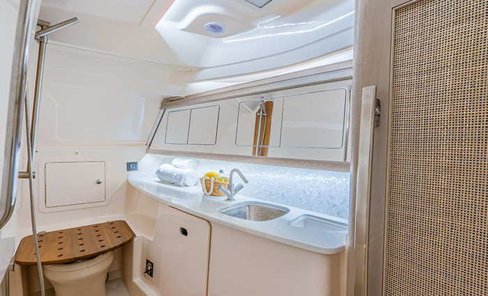 White bathroom featuring toilet, sink, cabinet space and trash.