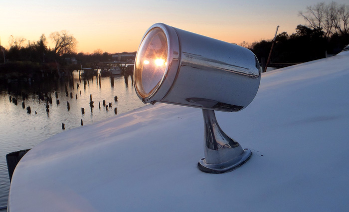 Fixed spotlight on the top of a white vessel in use at sunset.