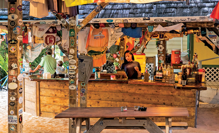 Female tending bar at a wooden establishment on the beach.