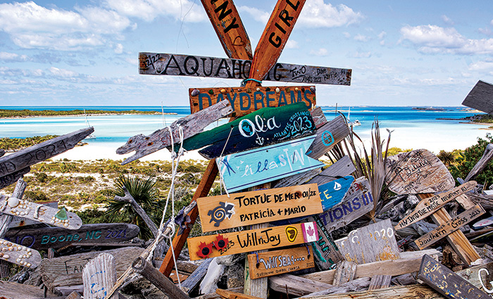 Numerous wooden signs stacked on the beach during a sunny day.