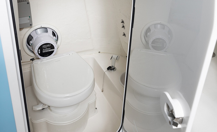 Small white toilet in white bathroom with glass door entry.