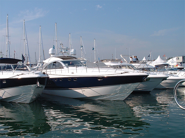 A row of white vessels docked in water on a sunny day.