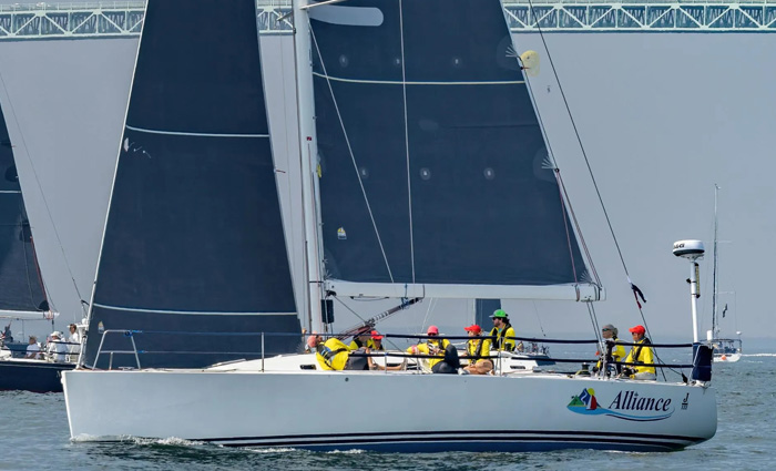 A white Alliance sailboat with navy blue out on open waters.