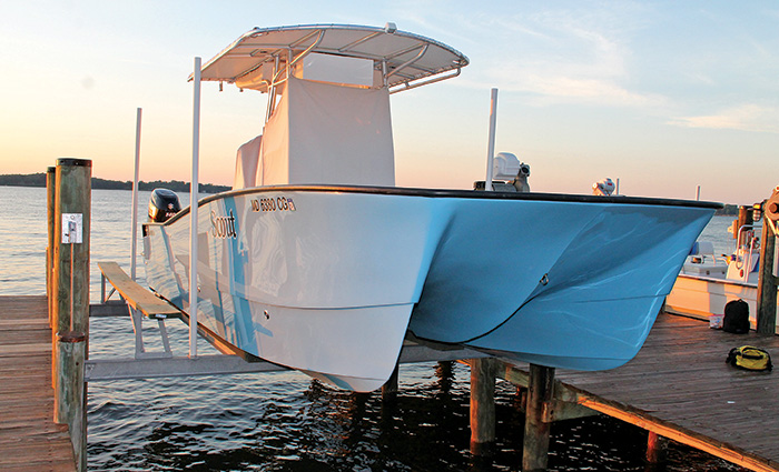 White vessel on a lift at a dock during sunset.