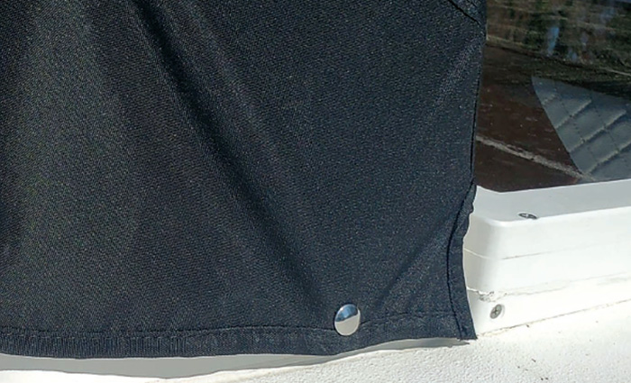 Black boat cover attached to a white vessel by a silver snap.