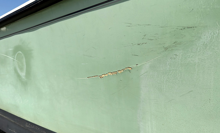 Damaged gelcoat on the side of a vessel where a docking accident occurred.