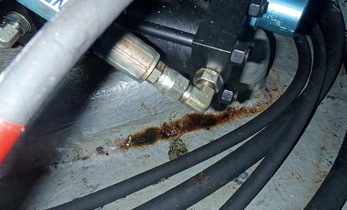 Close-up view of a hydraulic system showing rust as a result of leakage from black tubes.