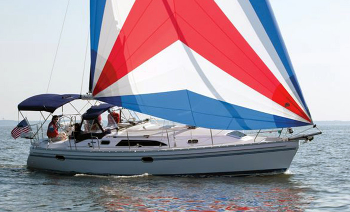Large white sailboat with red, white and blue sails and a navy canopy out at sea.