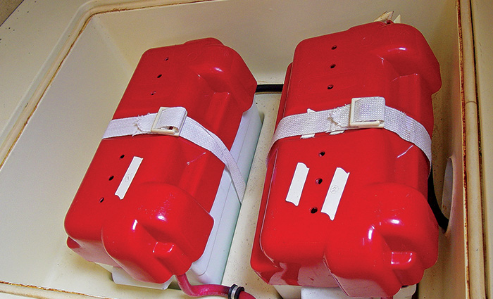 Two large red batteries side by side, each held down by a white strap.