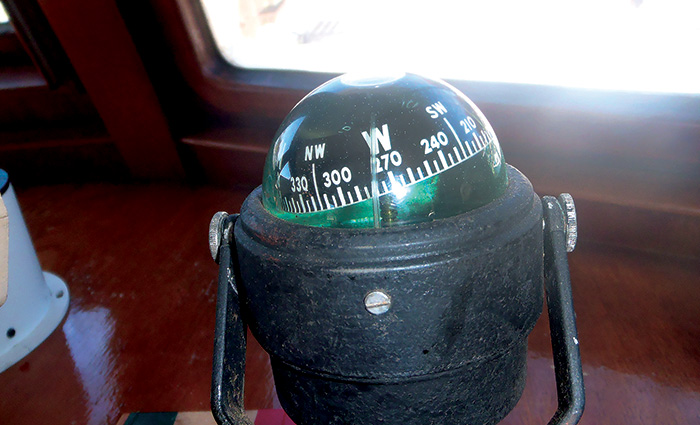 Black boat compass with white numbers and letters indicating West.