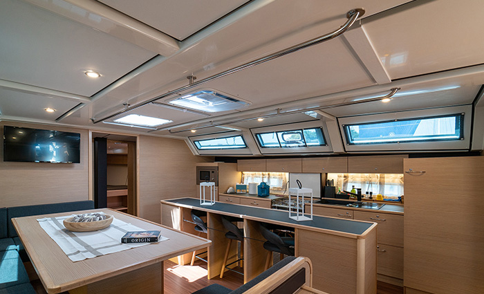 Kitchen layout featuring sitting area with table, television, tan cabinets, two skylights and three windows. 