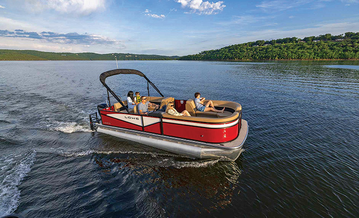 Family of six sitting comfortably on tan leather seats aboard a red and white pontoon boat on the water.