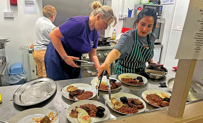 Three women in a kitchen dishing up a handful of plates filled with delicious Irish breakfasts.