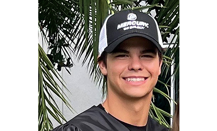 Young adult male wearing a black and white trucker hat and black shirt.