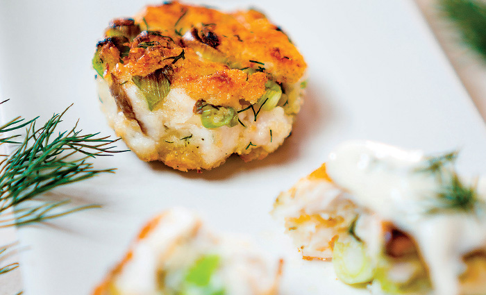 Small, circular fried fish filet on a white plate.
