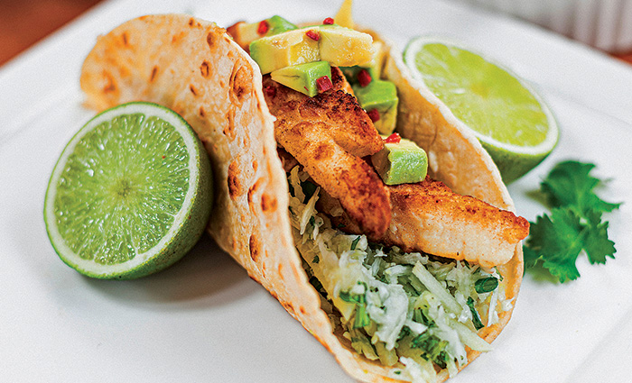 Fish taco with a sliced lime on each side