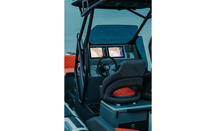 Helm on a vessel at dusk showcasing lit twin displays and a bucket seat.