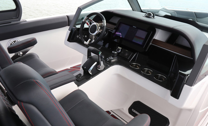 Vessel helm featuring black navigation display, black leather seats with red trim and digital switching system.