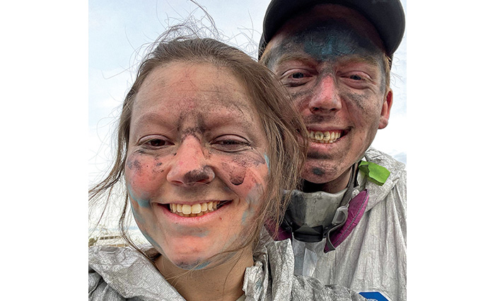 Young adult male and female taking a selfie while both faces covered in paint.