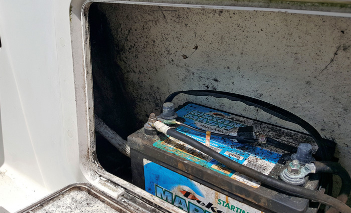 Black battery covered by mold in a boat compartment.