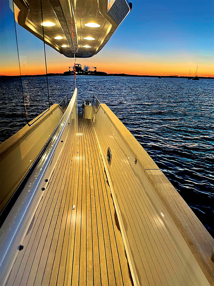 View of a golden sunset from the side of a vessel looking out on open waters.