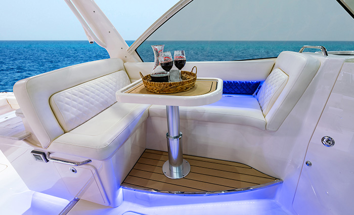 Wrap around white seating area and table on a white boat out on open waters with clear skies.
