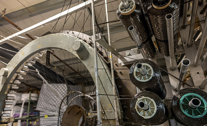 Large metal spoon inside a large warehouse with dark fabric being fed in.
