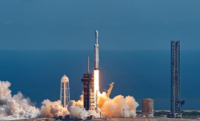 A large rocket  in the beginning stages of a launch with fire and smoke blasting from beneath.