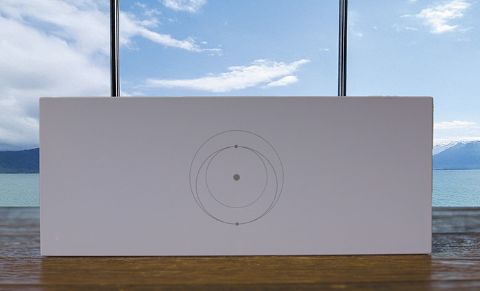 A white rectangle board with three overlapping circles and three little holes set on a wooden table with a window and blue skies in the background.