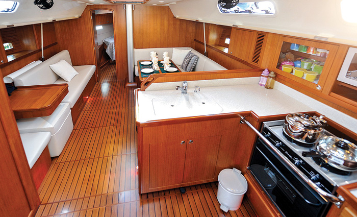 View of a boat cabin featuring wood floors, kitchen and sitting area.
