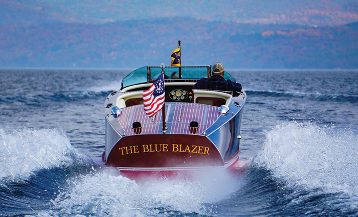 View from behind of a small vessel with 'The Blue Blazer' name and American flag on the back speeding through open waters.