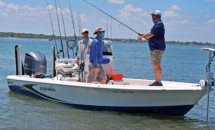 Three men on a small white boat fishing in open waters.