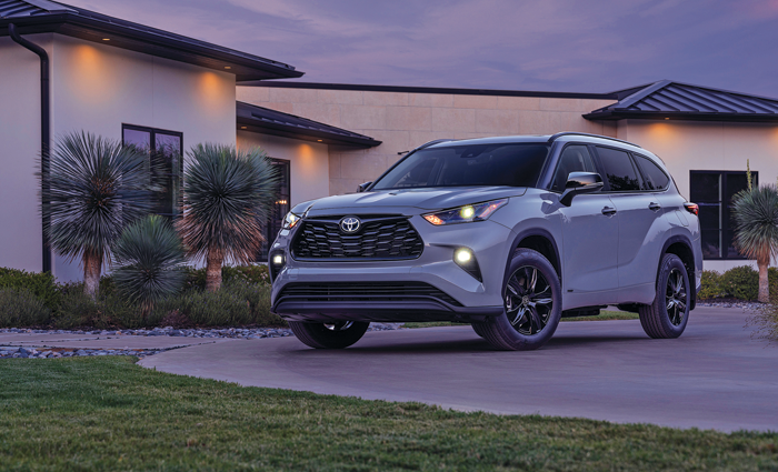 White Toyota Highlander HEV in a driveway at dusk.
