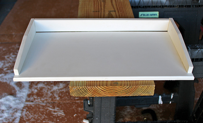 White shelf sitting on wooden board with remnants and dust in the background. 