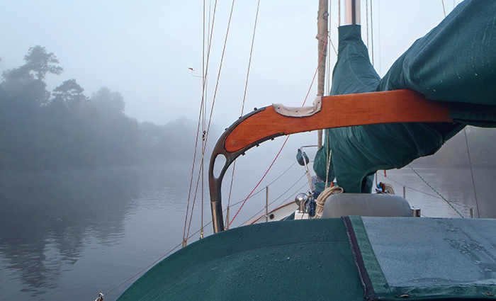 Large sailboat on open waters with dense fog in the foreground. 