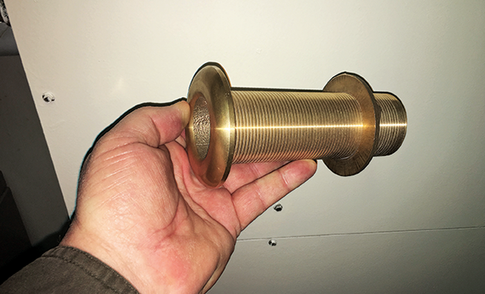 Hand holding a gold thru-hull.