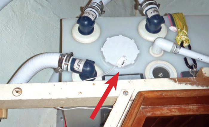 Red arrow pointing to a white cap on a holding tank.