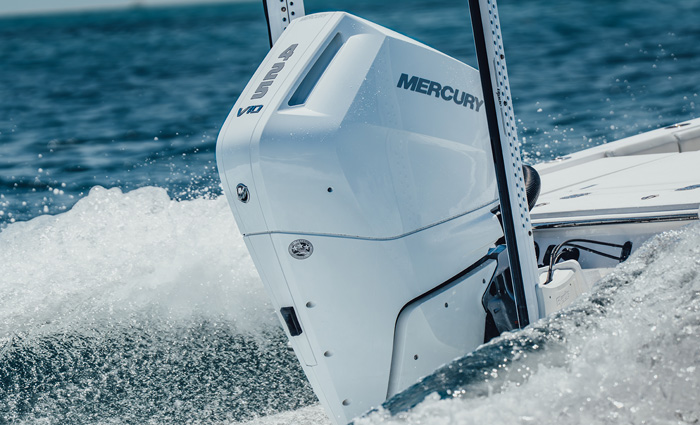 Up-close view of a white Mercury outboard engine in bright blue waters.