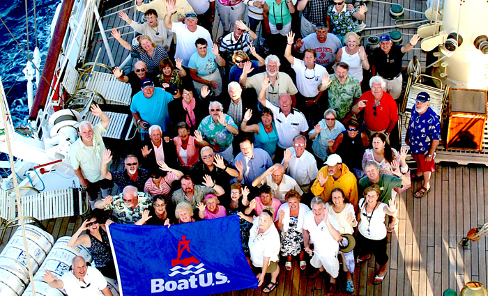 Group of adults on a boat holding a blue, red and white flag with BoatU.S. copy.